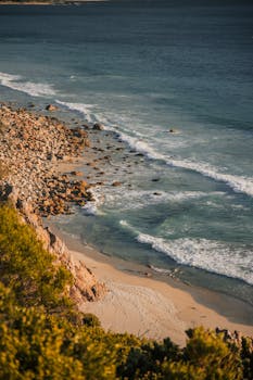 A stunning view of the rocky coastline and turquoise ocean waves in Cape Town, South Africa.