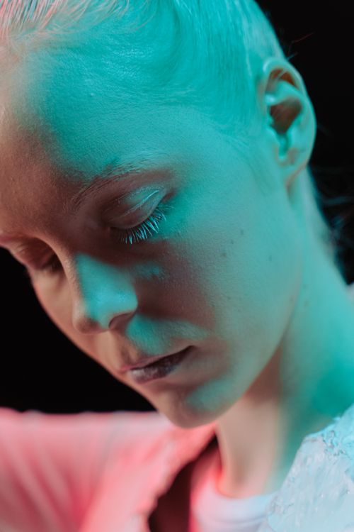 Free A dramatic close-up portrait of a woman with eyes closed, showcasing vibrant lighting effects. Stock Photo