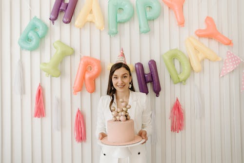 Free Woman Holding a Cake and Wearing a Party Hat Stock Photo