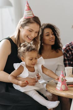 Smiling women and child enjoying a birthday party indoors with party hats and joy.