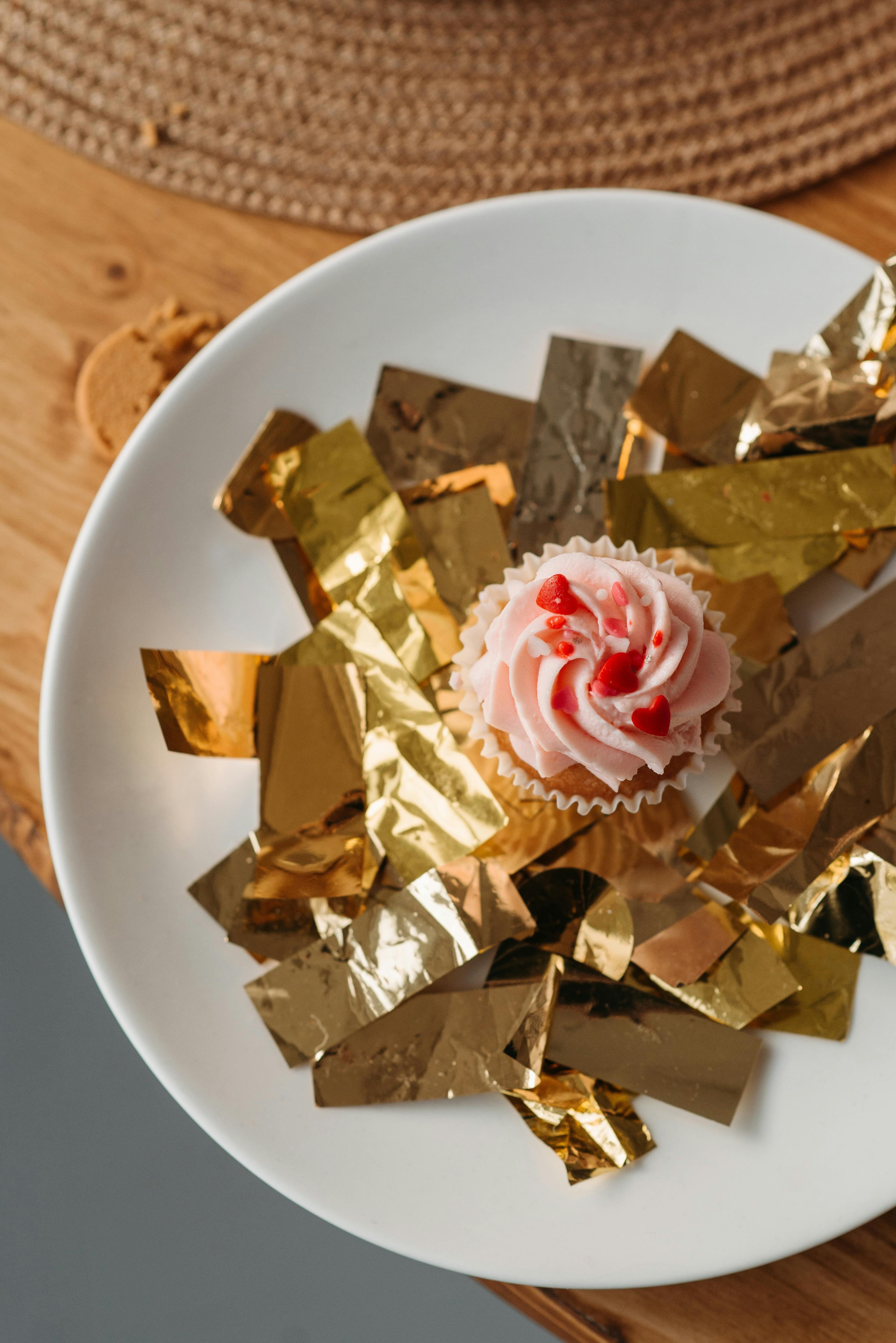 view from top shot of a cupcake with whipped cream on golden confetti