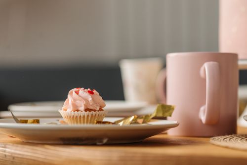 Free A close-up view of a pink frosted cupcake on a table setting. Stock Photo