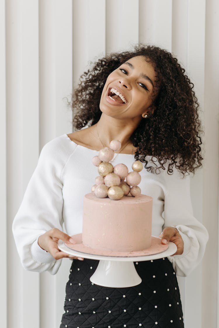 Woman With Curly Hair Holding A Pink Cake