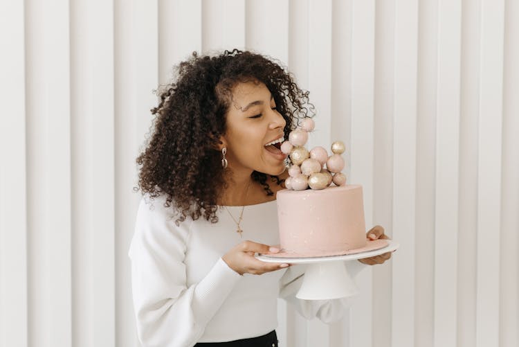 Woman With Curly Hair Eating A Pink Birthday Cake