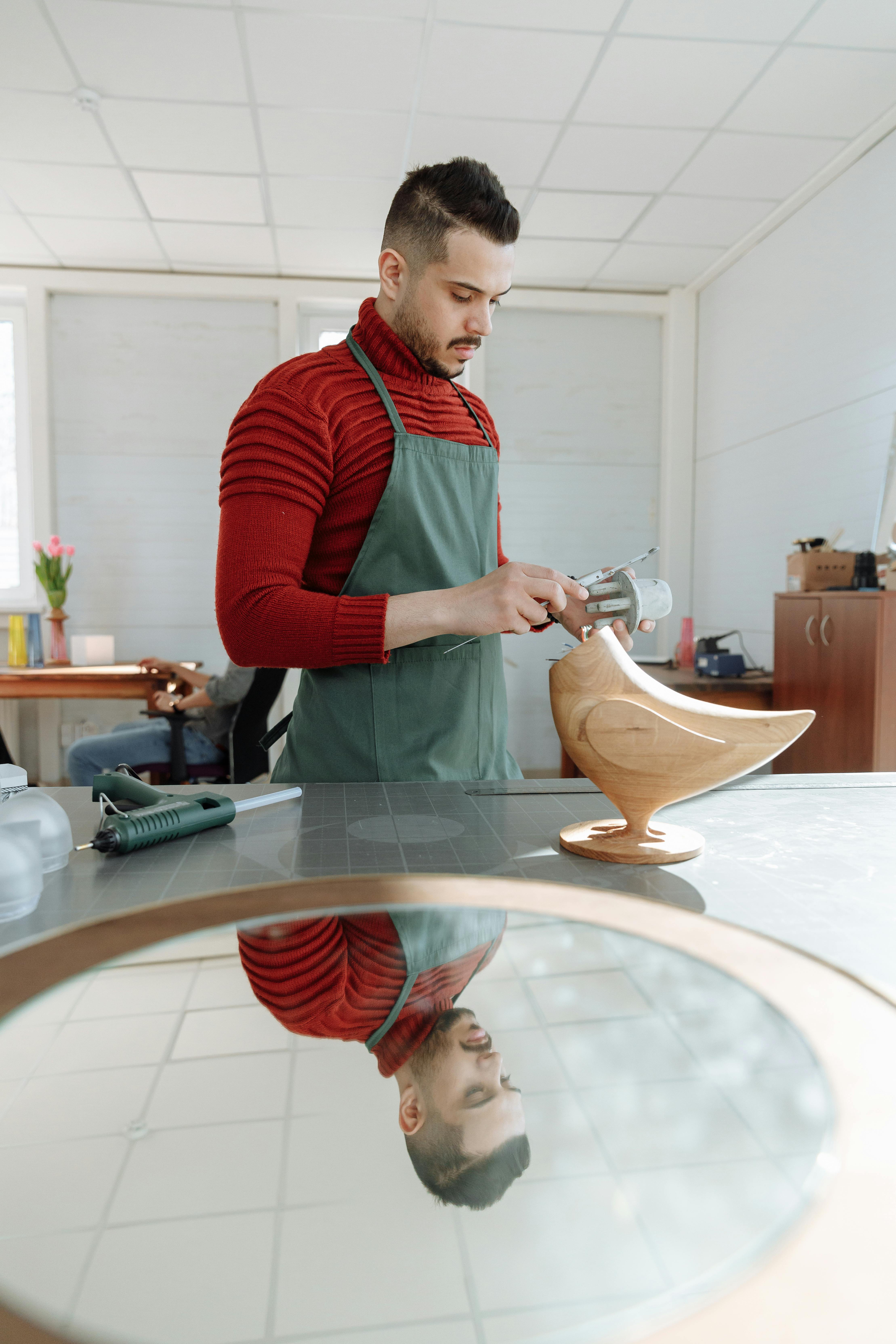 man wearing an apron crafting in a workshop