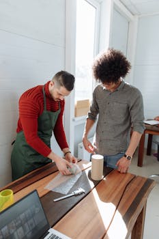 Two young men packing products in a sunlit workspace, symbolizing teamwork and small business innovation.