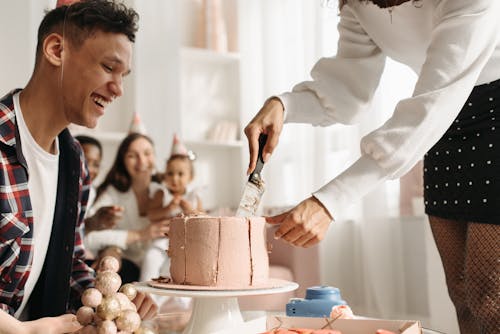 Free Woman Slicing a Cake Beside a Man with Party Hat Stock Photo