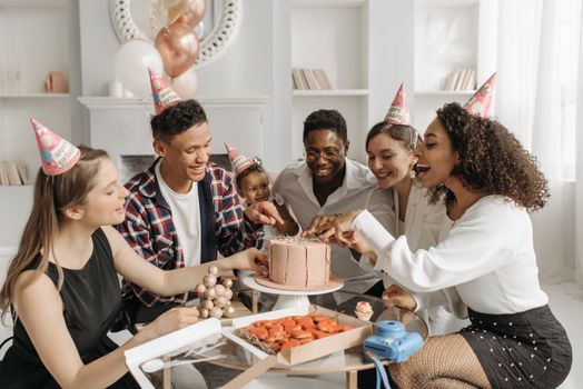 A cheerful birthday party with friends enjoying cake and laughter indoors.