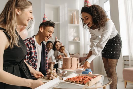 Group of friends celebrating a birthday indoors with cake and laughter.