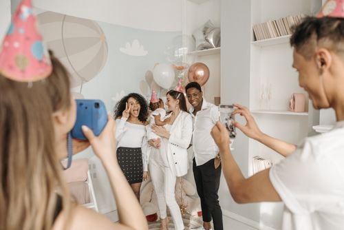 Free Group of friends celebrating a birthday indoors with balloons and party hats, captured in a joyful moment. Stock Photo