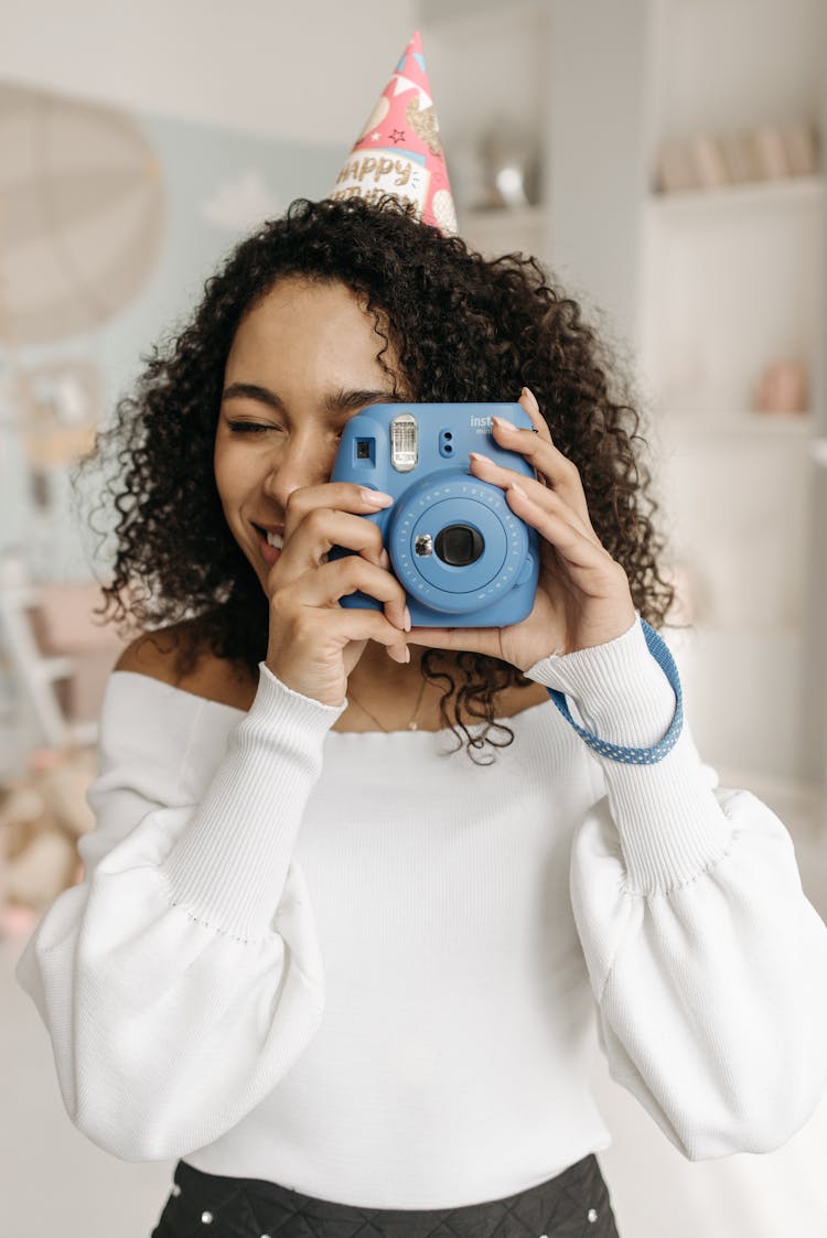 A Woman In White Long Sleeve Shirt  Holding A Blue Camera