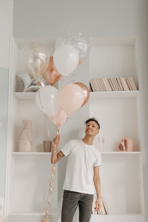 A Young Man in White Crew Neck T-shirt Holding Assorted Balloons