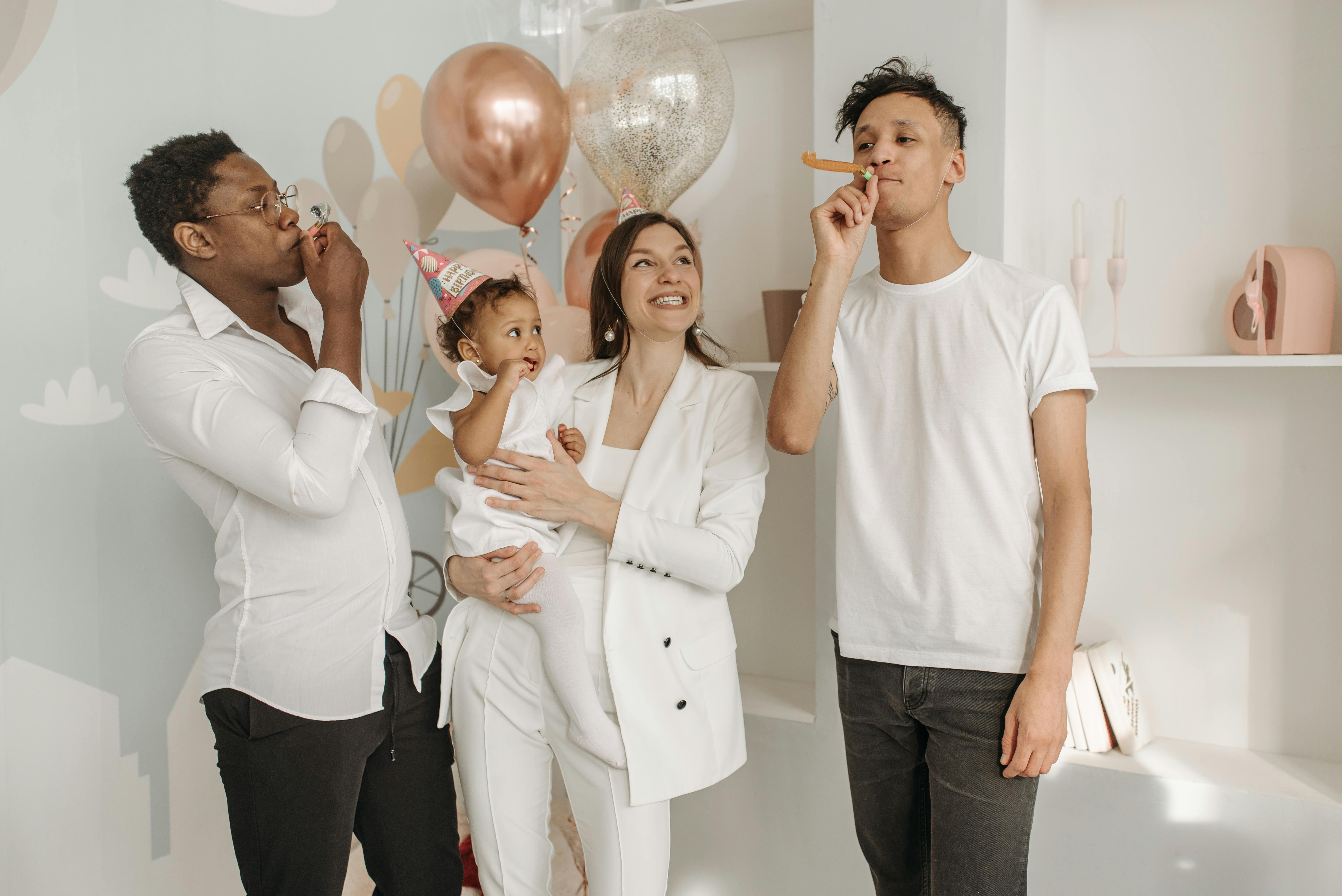 a couple with a child looking at a young man blowing party horn