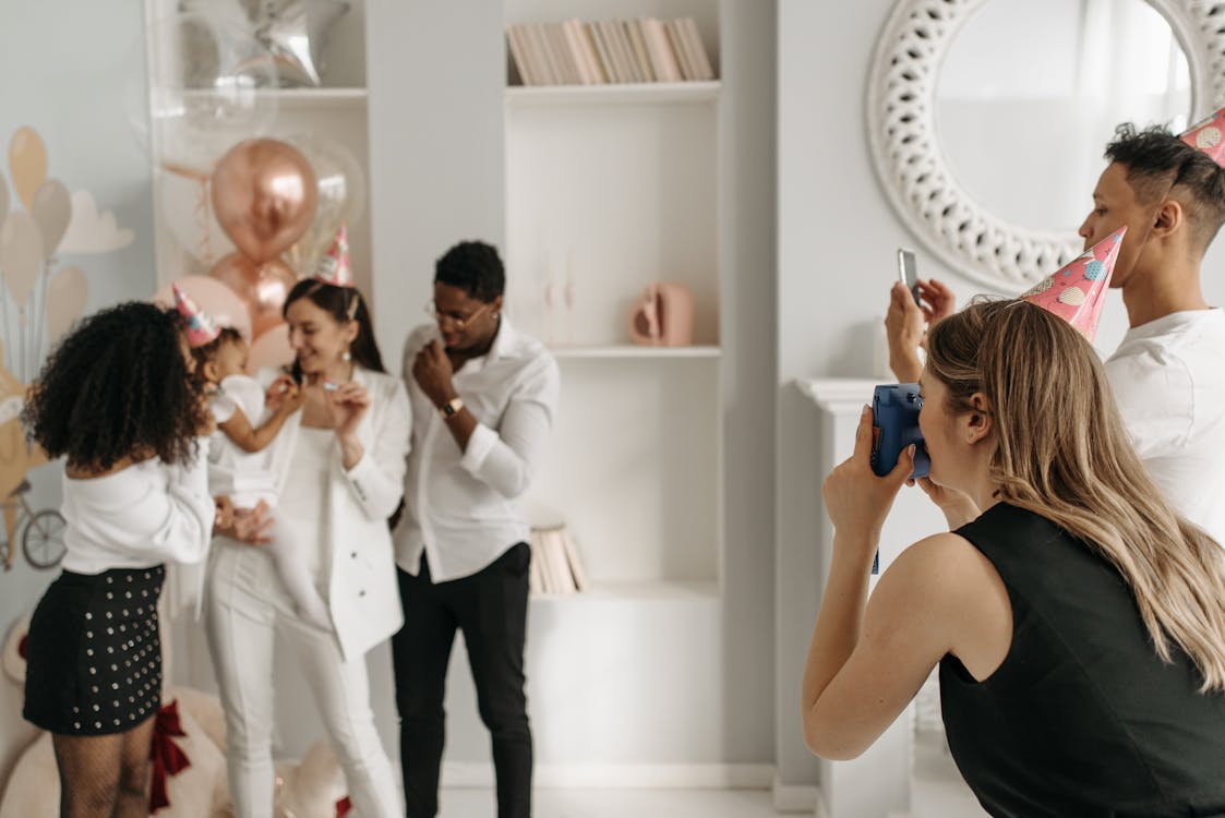 A Woman and a Man with Party Hats Taking Photo of a Family