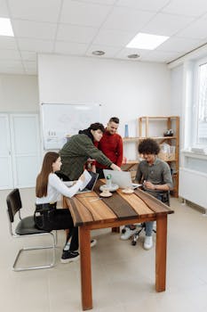 Team of colleagues collaborating over a laptop in a bright workspace.