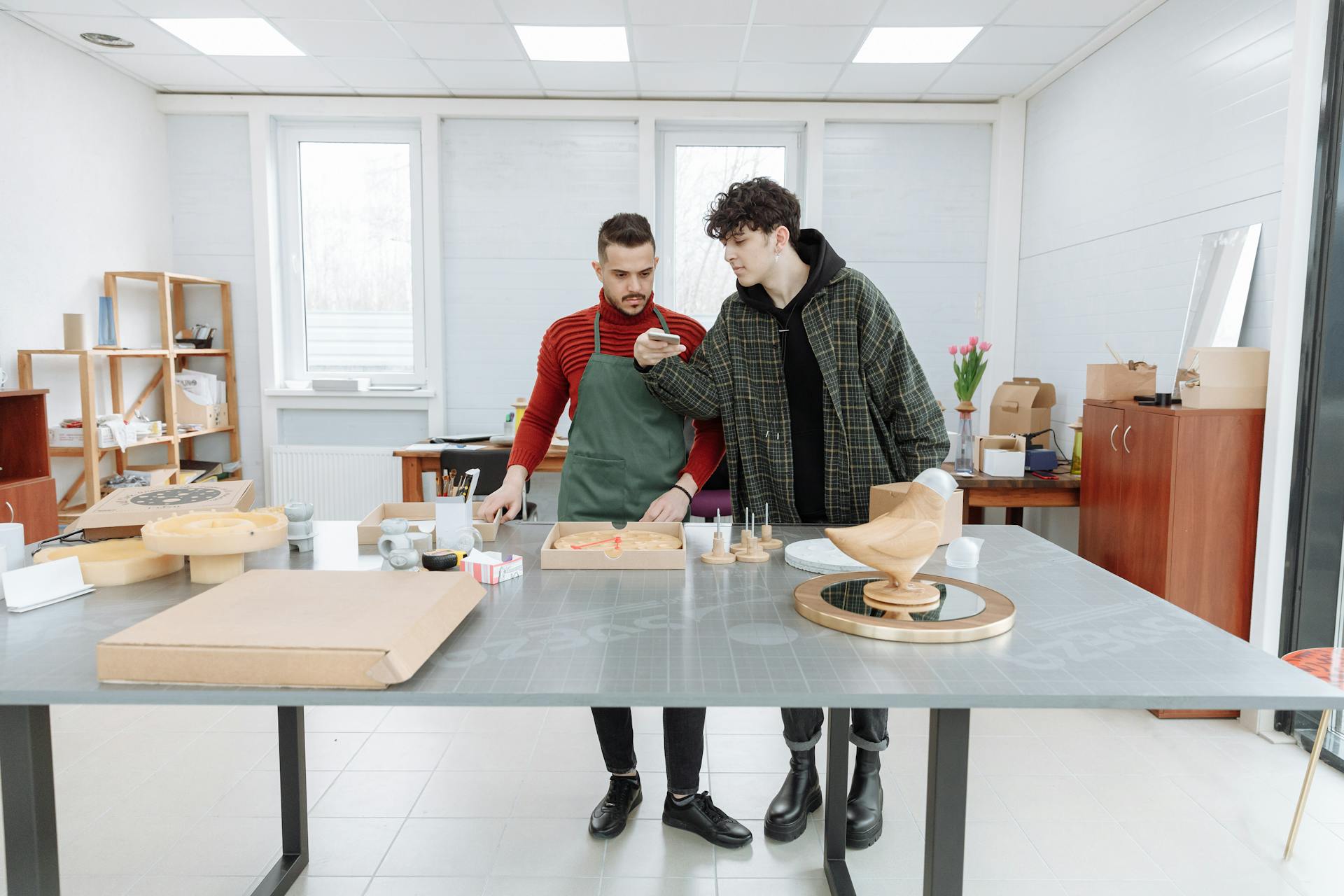 Two young men crafting and collaborating in a bright, modern workshop filled with tools and materials.