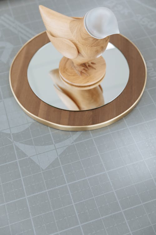 Free Wooden Figurine of a Bird on Mirror and Wooden Base Stock Photo