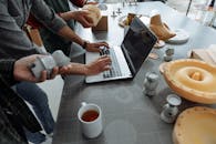 People Standing Beside Man Using Laptop on Gray Table with Silicon Forms
