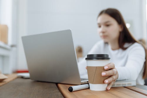 Free Woman Working on Her Laptop on a Wooden Table Stock Photo