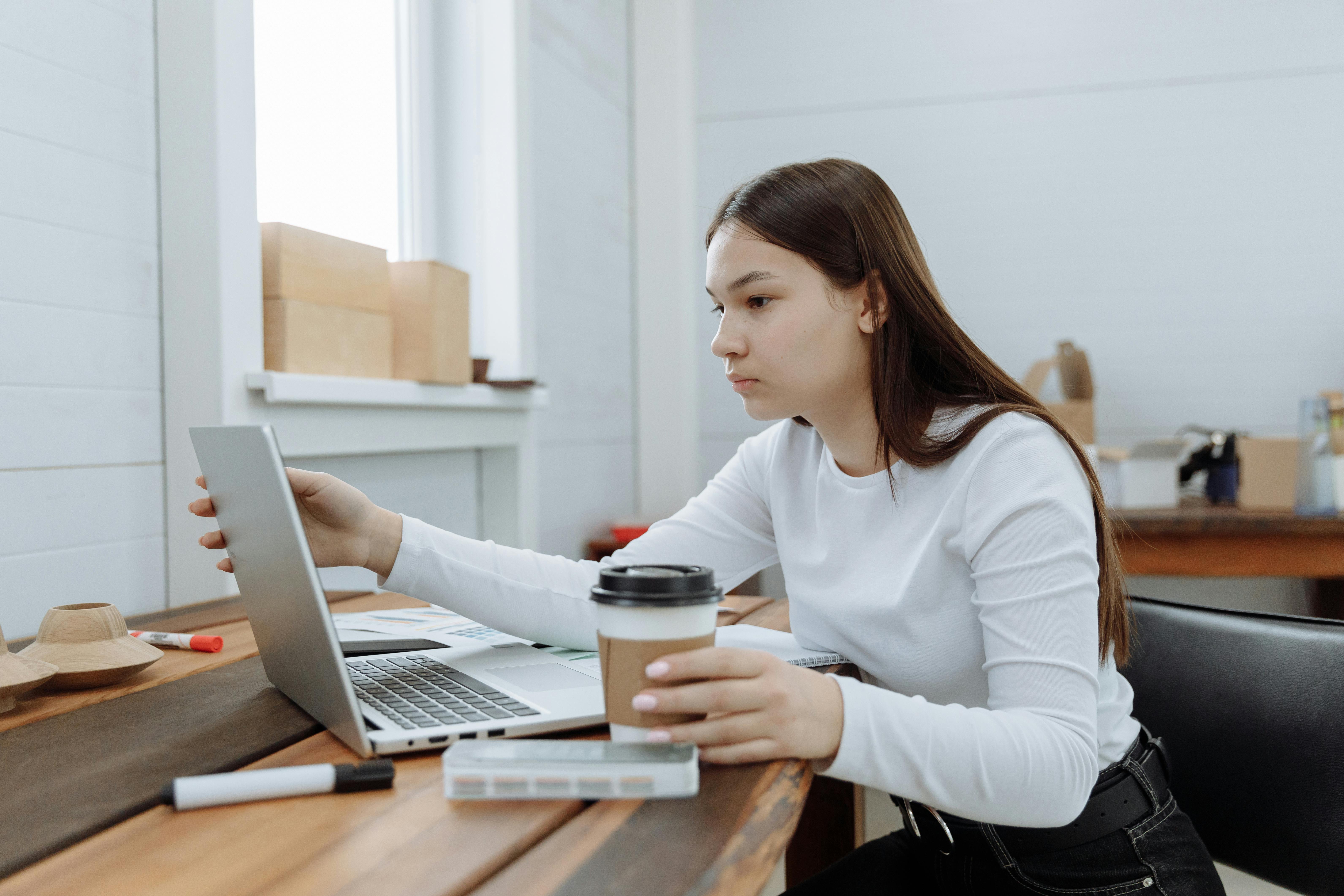woman in white long sleeve shirt using macbook air on brown wooden table