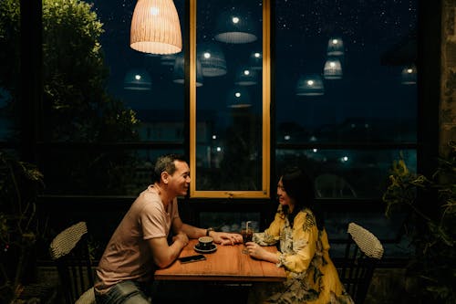 Man and Woman Sitting on Brown Wooden Table