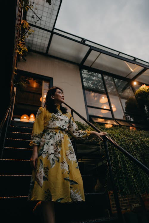 Woman in Yellow Floral Dress Standing on Stairs Free Stock Photo