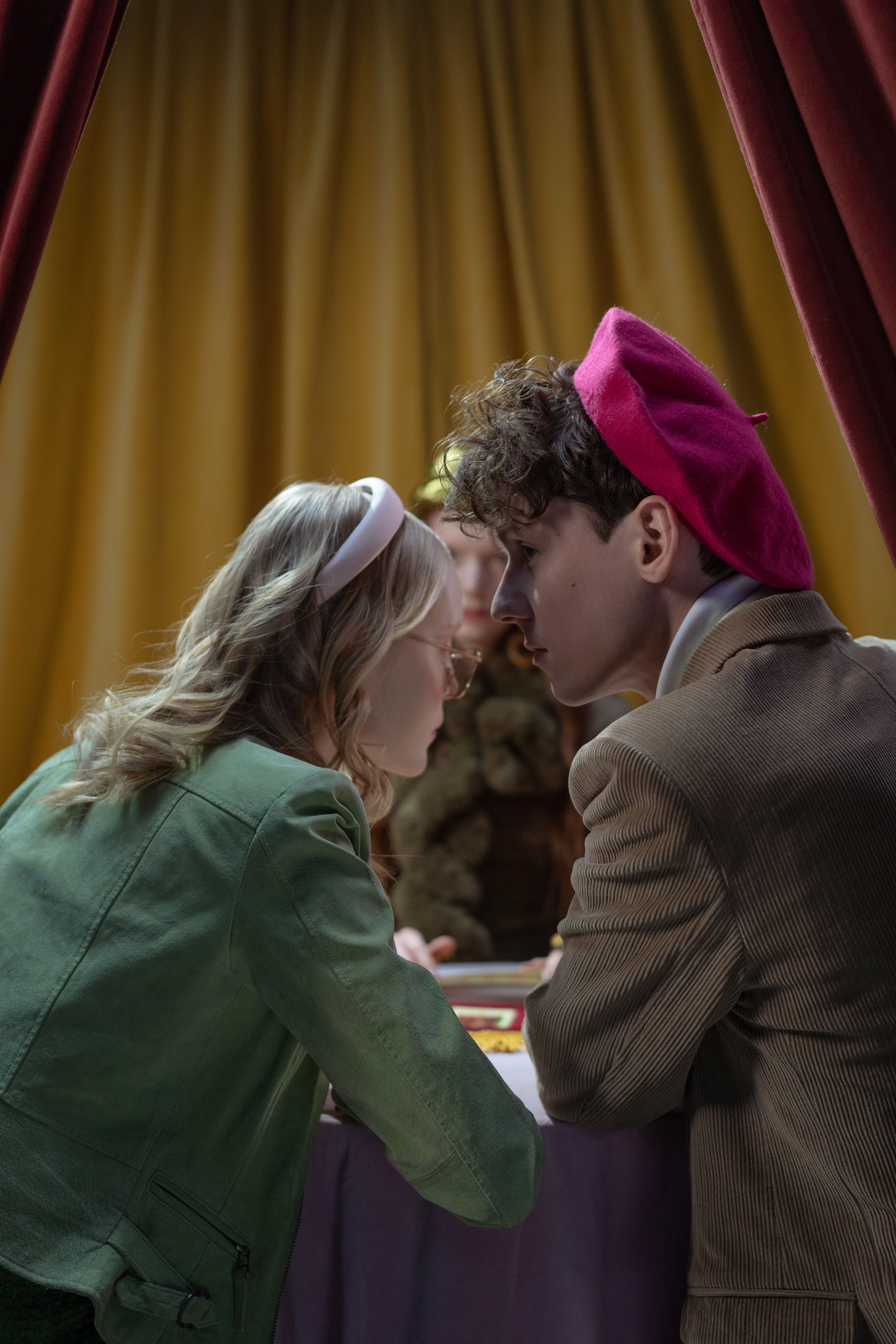 A young couple engages deeply with a fortune teller in a mystical setting.
