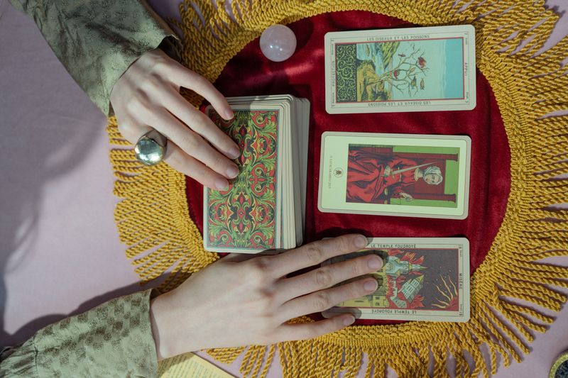 Hands placing cards on a red velvet cloth