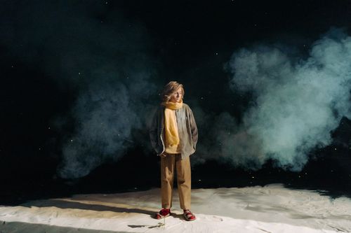 Free A woman wearing a yellow scarf stands amid dramatic smoke on a dark backdrop, creating a mysterious atmosphere. Stock Photo