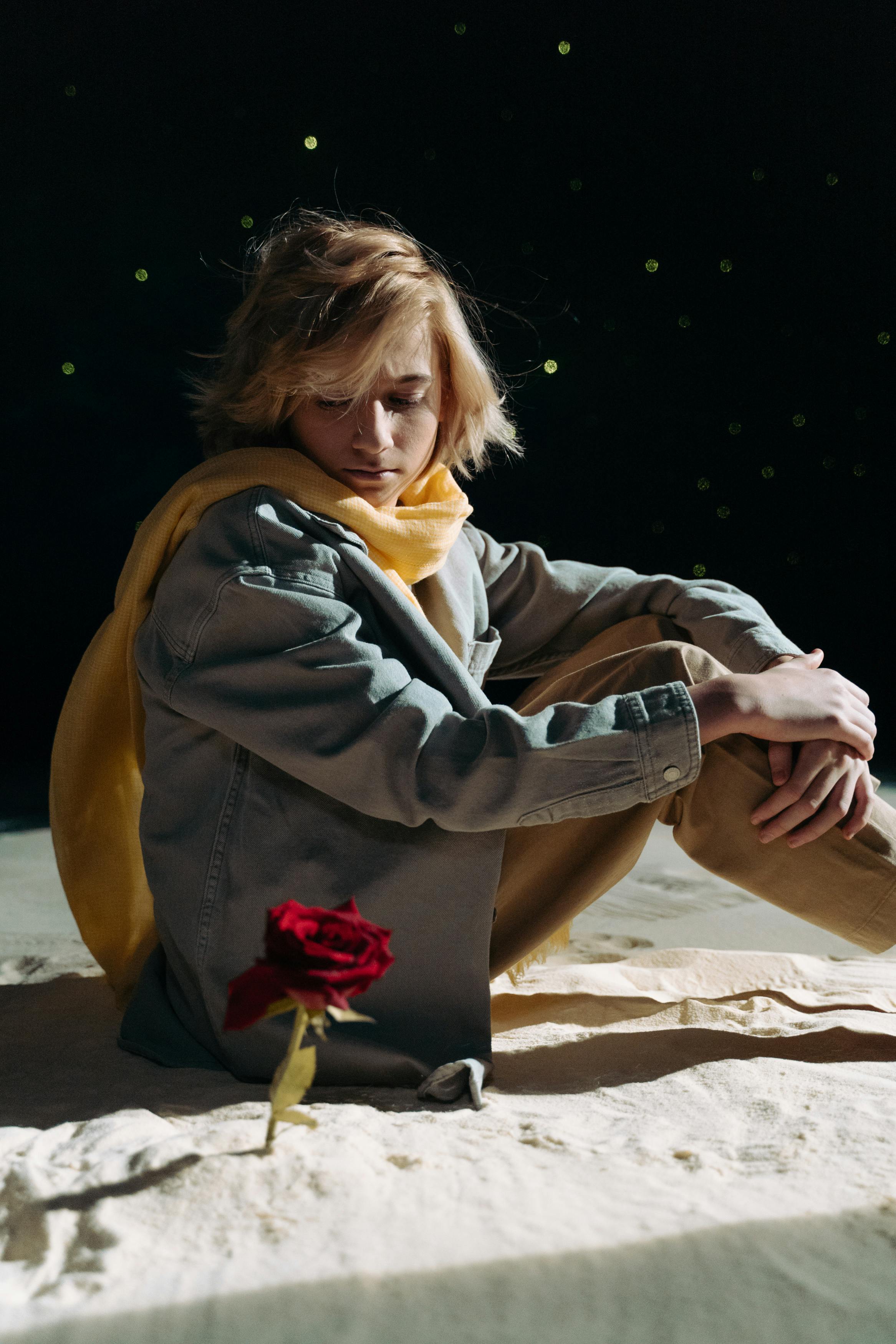 boy with yellow scarf looking at a red flower