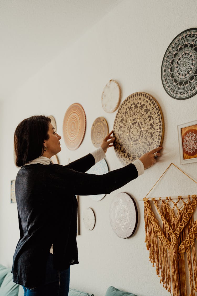 Woman Decorating Wall With Round Wooden Mandala Panels