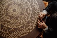 Intricate mandala art being hand drawn on canvas, showcasing detail and artistry.