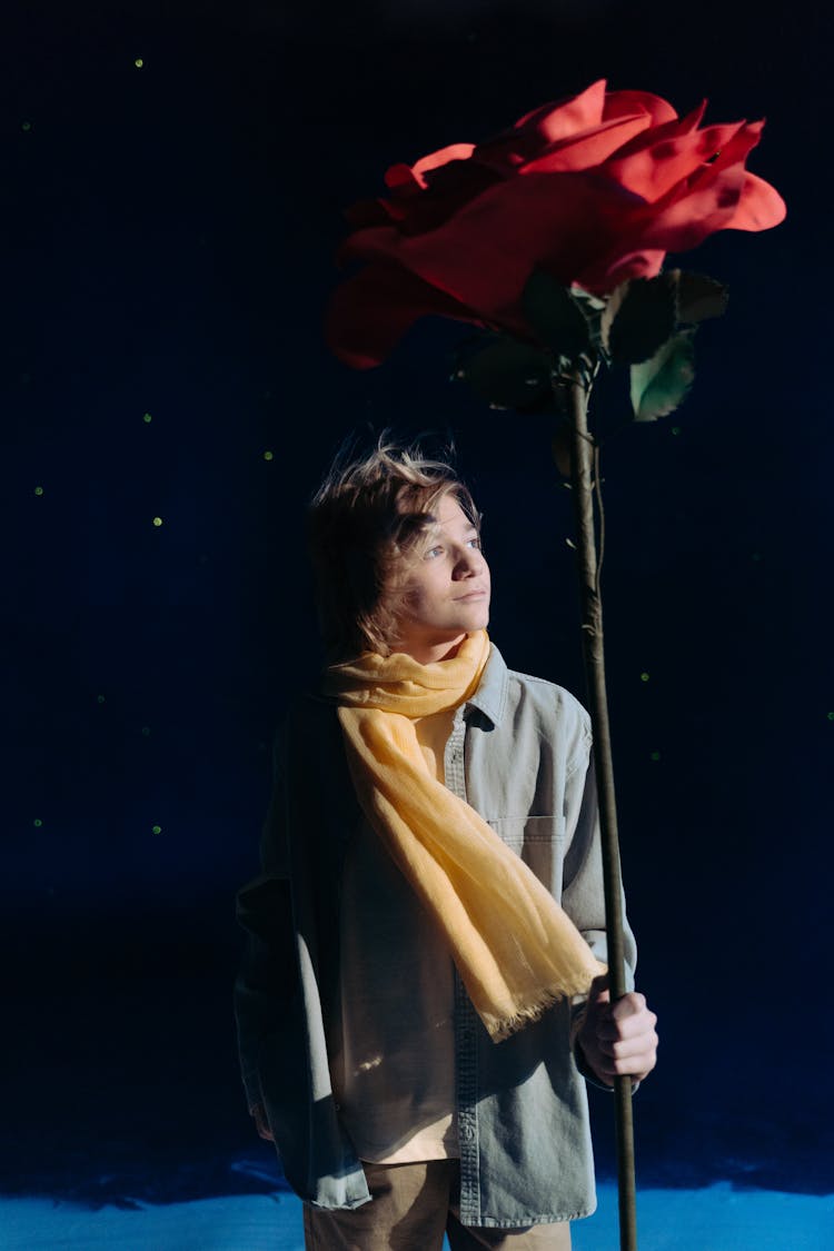 Boy With Yellow Scarf Holding A Red Flower