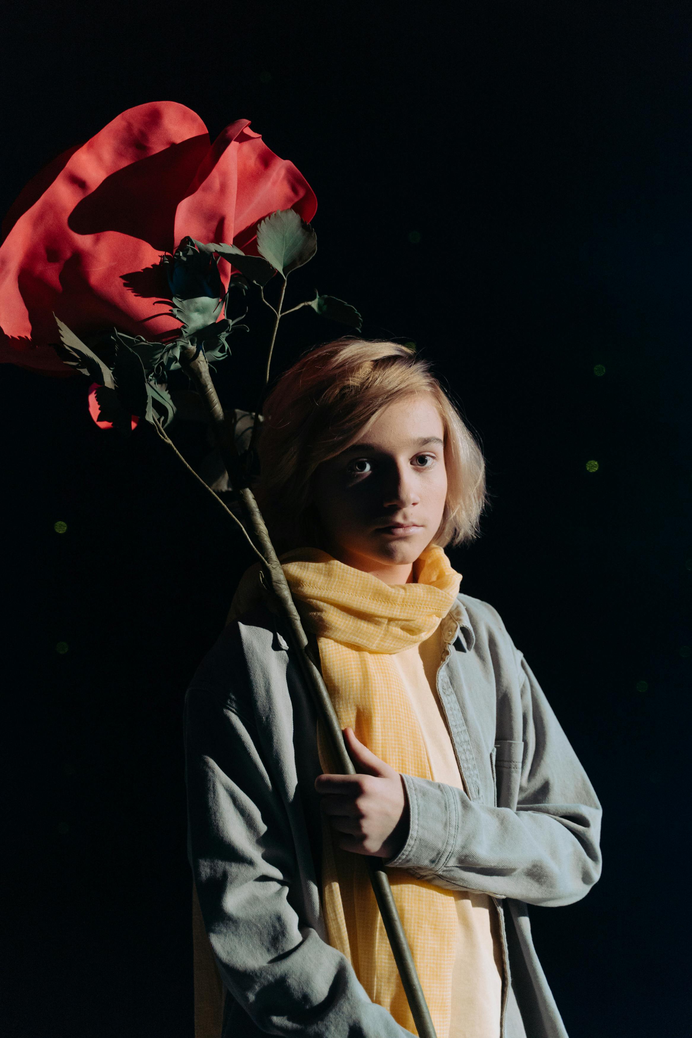 boy with yellow scarf holding big red rose