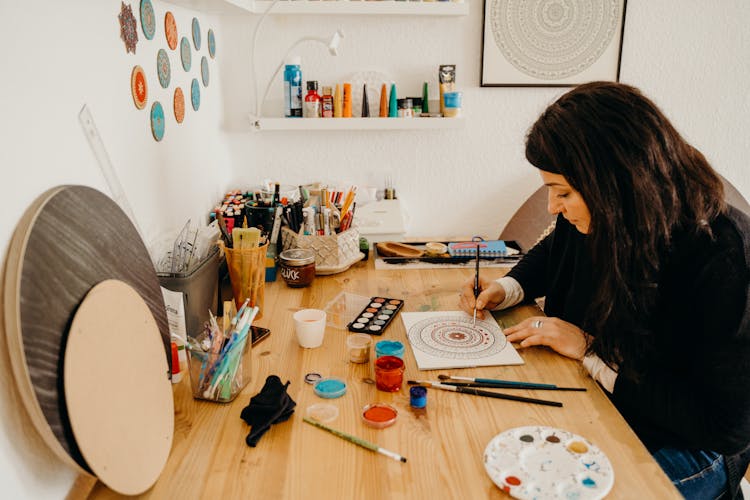 Woman Painting Mandala Design On A White Paper