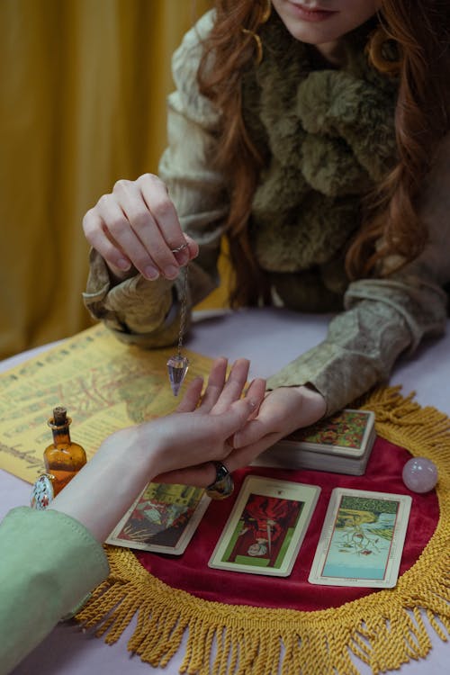 Free A Fortune Teller Holding a Hand of a Person While Reading a Tarot Cards Stock Photo