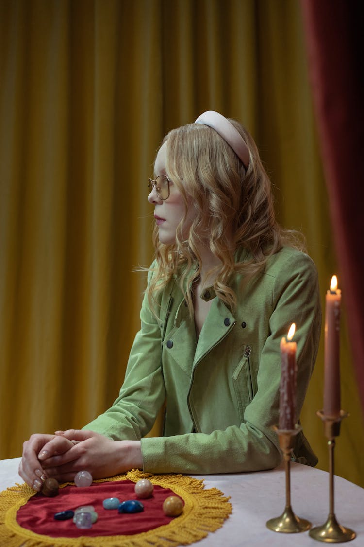 A Woman In A Trendy Jacket Sitting At A Table With Gemstones