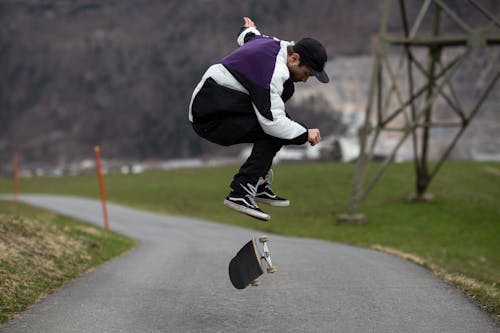 Free Man in White and Purple Jacket using Black Skateboard Stock Photo