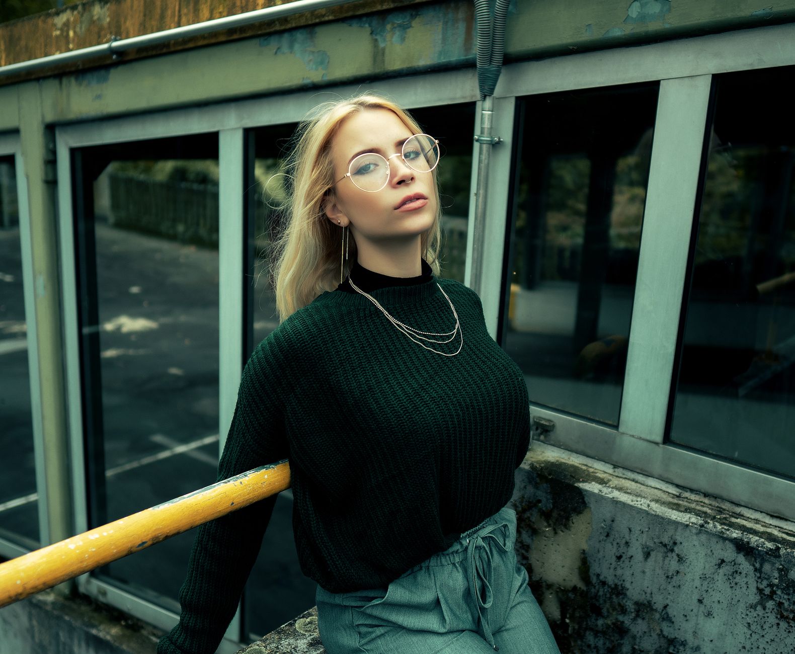 Femme en pull en maille vert oversize dans un décor urbain industriel