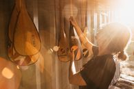 Side view of young female athlete taking wooden canoe oar from ribbed wall in back lit