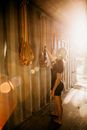Side view of anonymous barefoot female athlete choosing canoe oar in construction in back lit