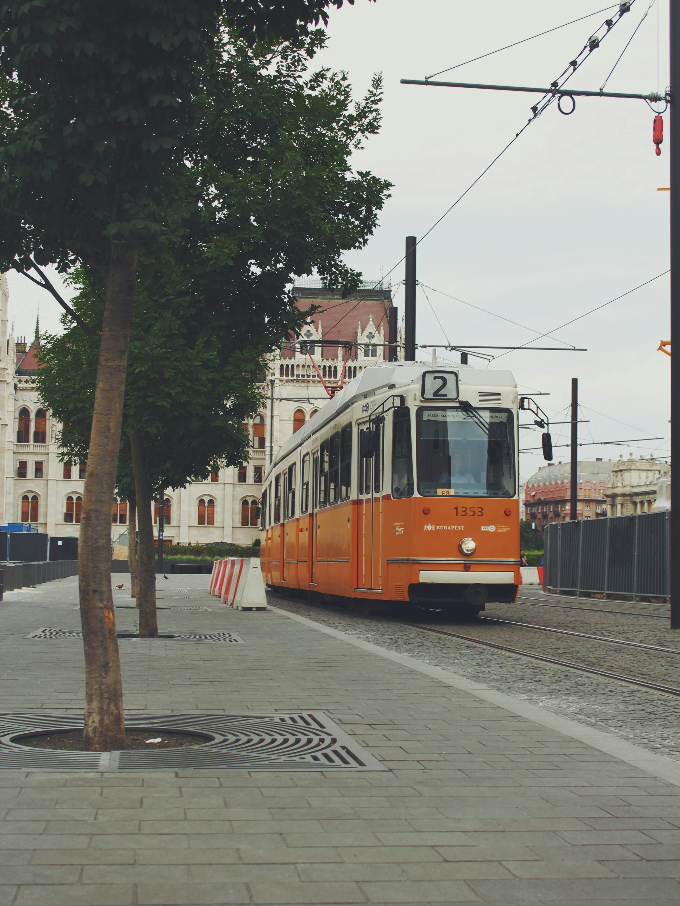 Free Vintage tram number 2 in Budapest glides past iconic Parliament building, offering a scenic urban scene. Stock Photo