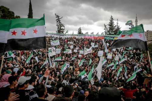 Free Large crowd gathering in Idlib, Syria, demonstrating with flags and signs. Stock Photo