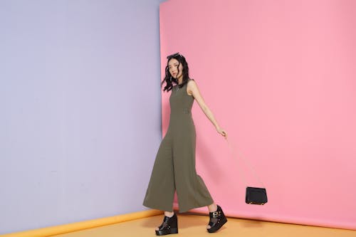 Full body of slender young female in trendy gray outfit looking at camera in corner of pink and blue walls