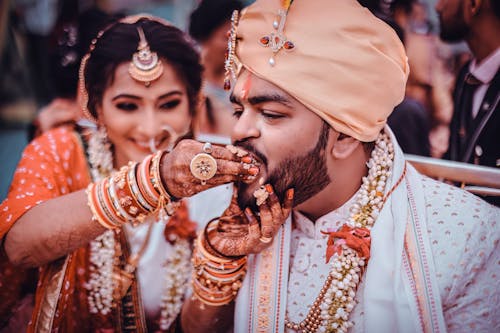 Free Woman with Mehndi Patterns and Jewelry Feeding Bearded Man in White Clothes and Turban Stock Photo