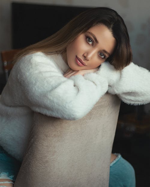Beautiful Woman in White Fur Coat Leaning on a Chair
