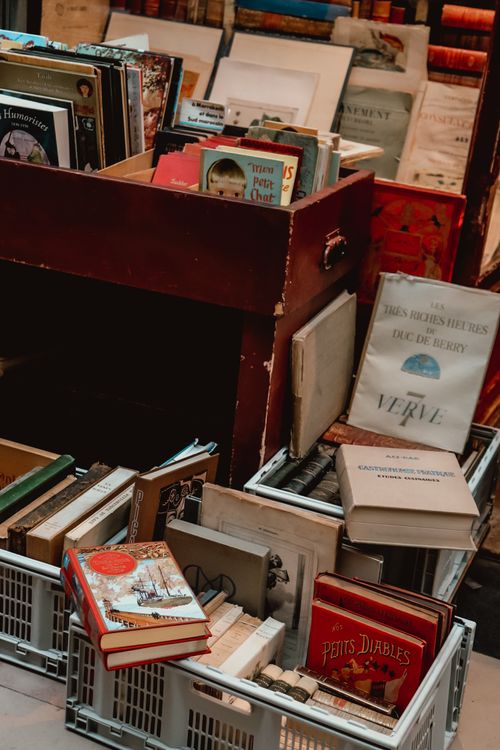 Free A collection of vintage books on display in a cozy bookstore corner with books stacked in crates. Stock Photo