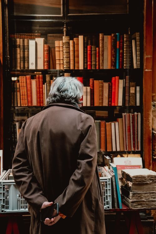 Free A man with gray hair in a bookstore, surrounded by shelves of vintage books. Stock Photo