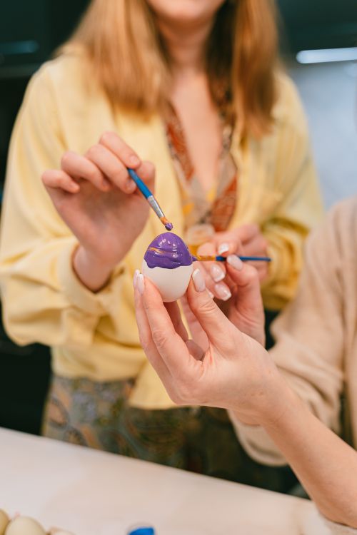 Free Two women decorating eggs with vivid paint indoors, demonstrating artistic creativity. Stock Photo