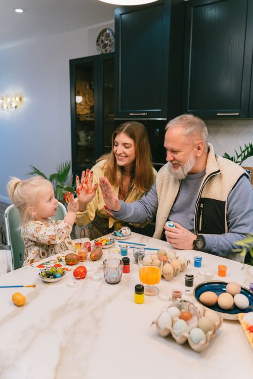 Free A family enjoying painting eggs together at home, highlighting bonding and creativity. Stock Photo
